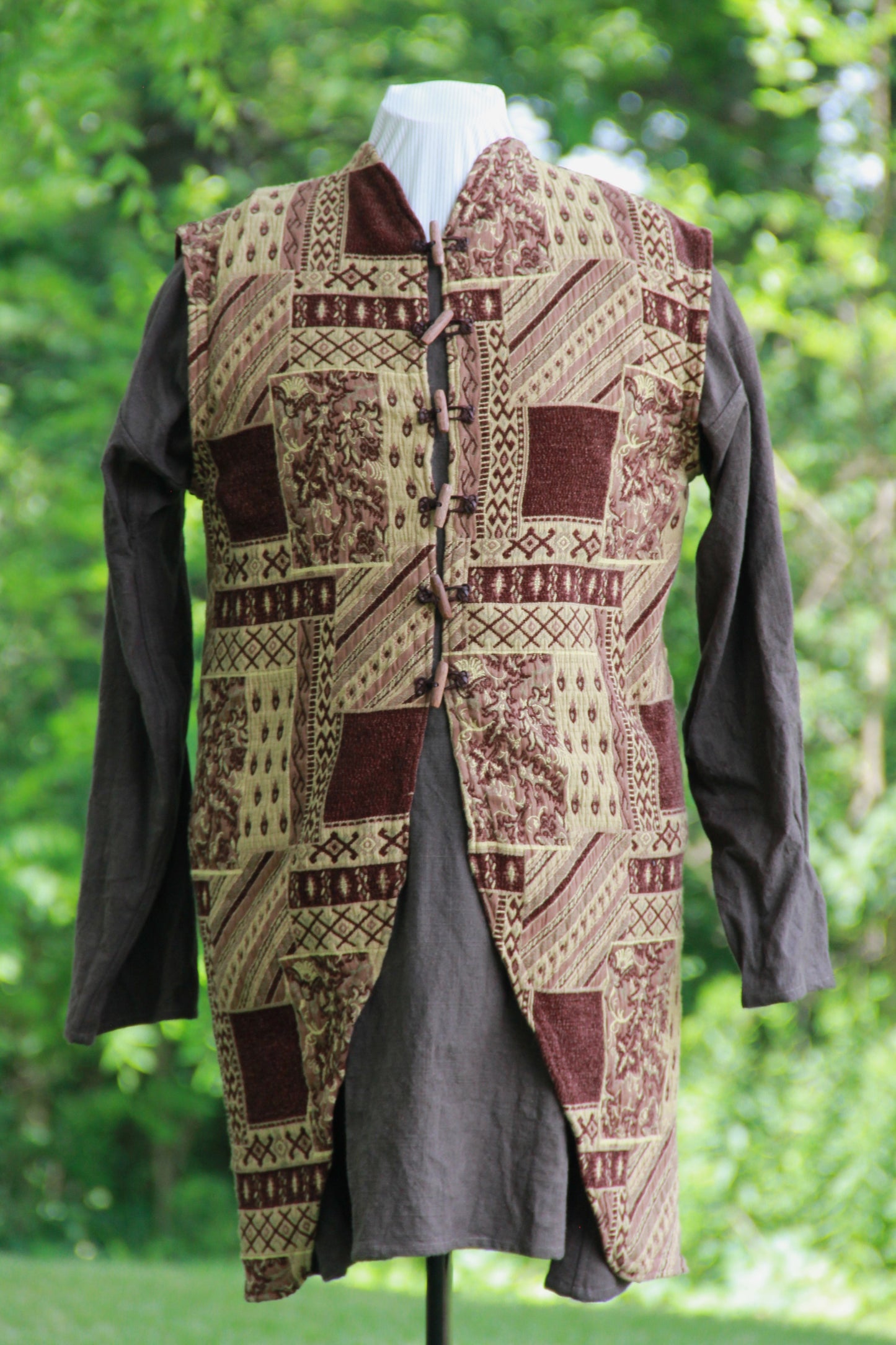 A hand made patchwork patterned chenille medieval jerkin in brown with leather and wooden hand carved toggles by west creek craftsman