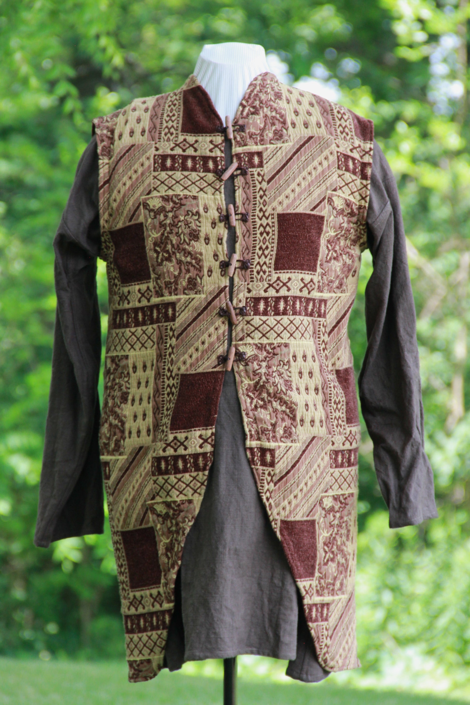 A hand made patchwork patterned chenille medieval jerkin in brown with leather and wooden hand carved toggles by west creek craftsman